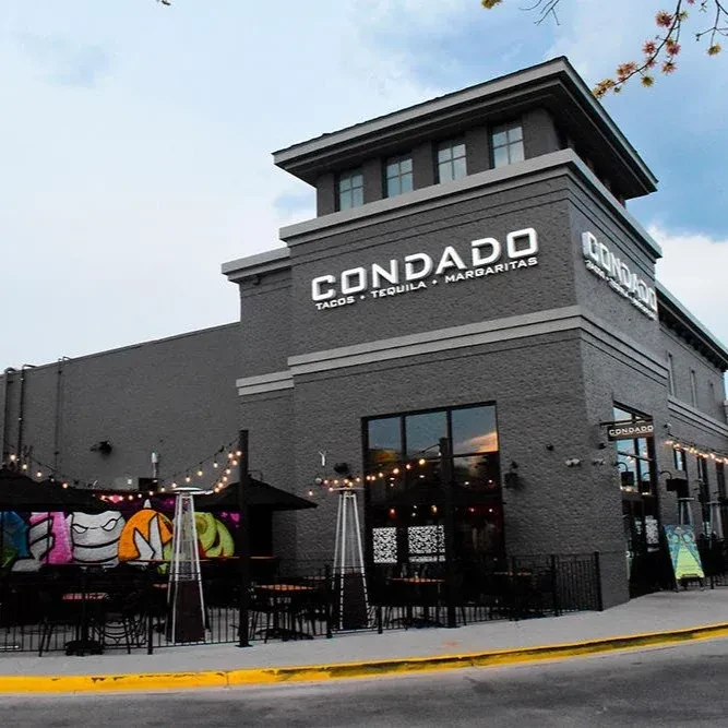 Modern Condado Tacos restaurant exterior with patio and colorful mural.