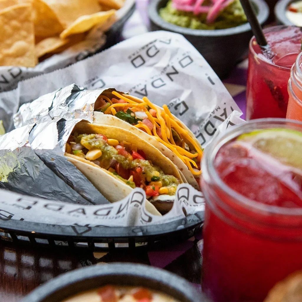 Two ONDA TACO tacos in a basket, with chips and drinks.