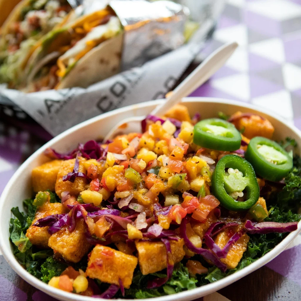 Colorful bowl with kale, crispy protein cubes, and fresh salsa.