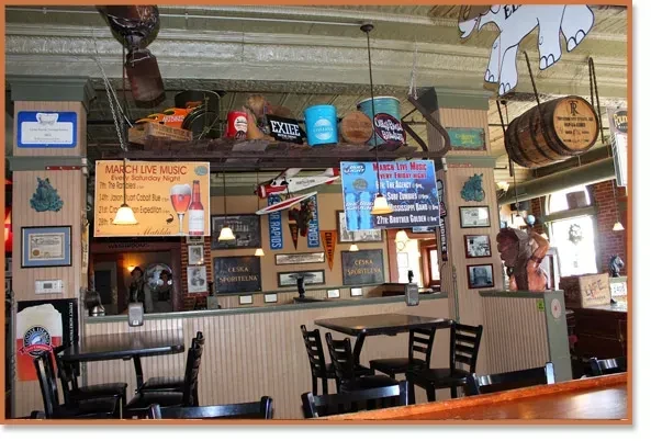 Eclectic, rustic restaurant bar interior with decorated walls and live music posters.