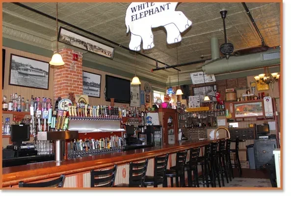 Classic pub interior, wooden bar, liquor, beer taps, "White Elephant" sign.