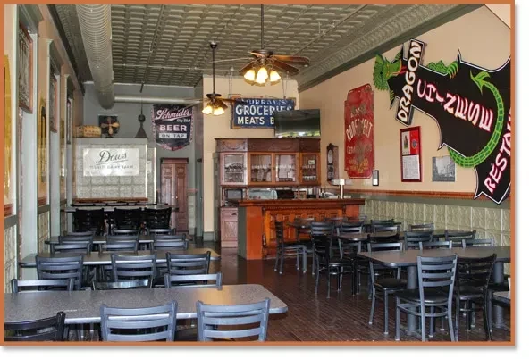 Empty vintage restaurant interior with ornate bar and multiple historic signs.