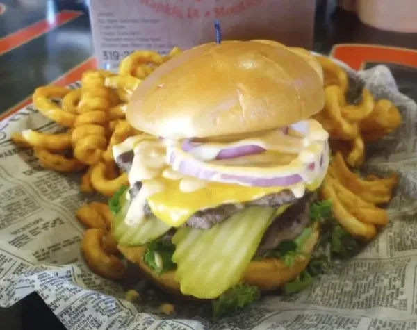 Close-up of a double-patty burger, cheese, and curly fries.