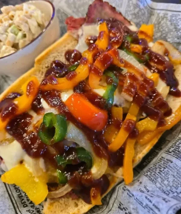 Generously filled sub sandwich with meat, cheese, peppers, and BBQ sauce.