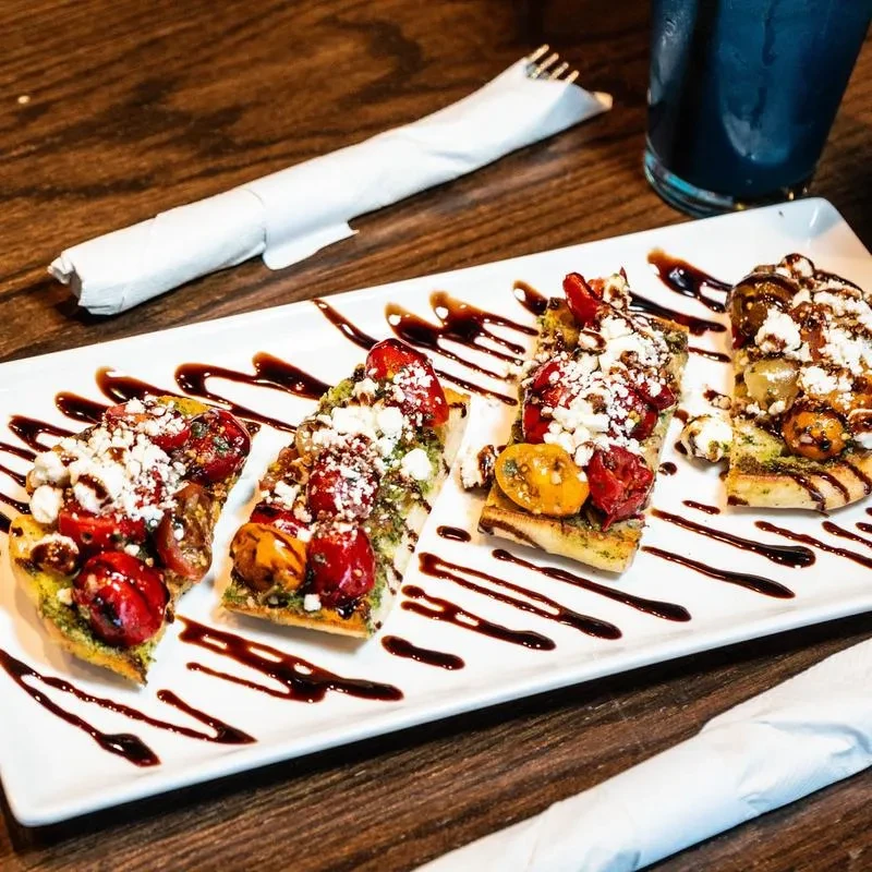 Bruschetta with roasted tomatoes, pesto, feta, and balsamic glaze.