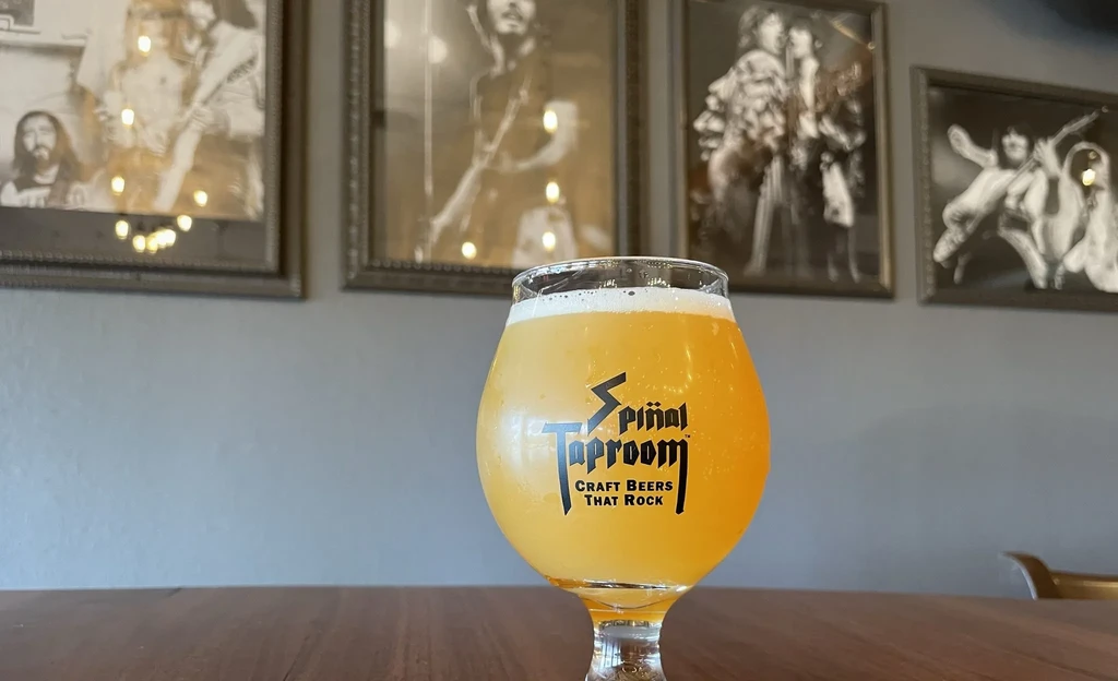 Close-up of hazy beer in Spinal Taproom goblet, blurred music background.