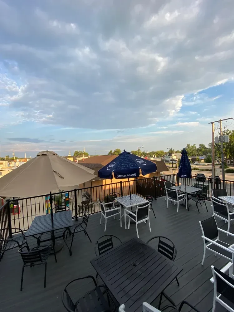 Empty rooftop patio with tables, chairs, and Samuel Adams umbrellas.