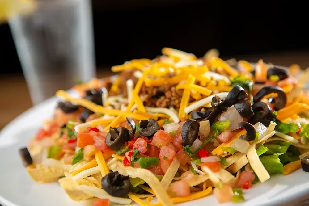 Loaded nachos with meat, cheese, olives, tomatoes, and peppers.