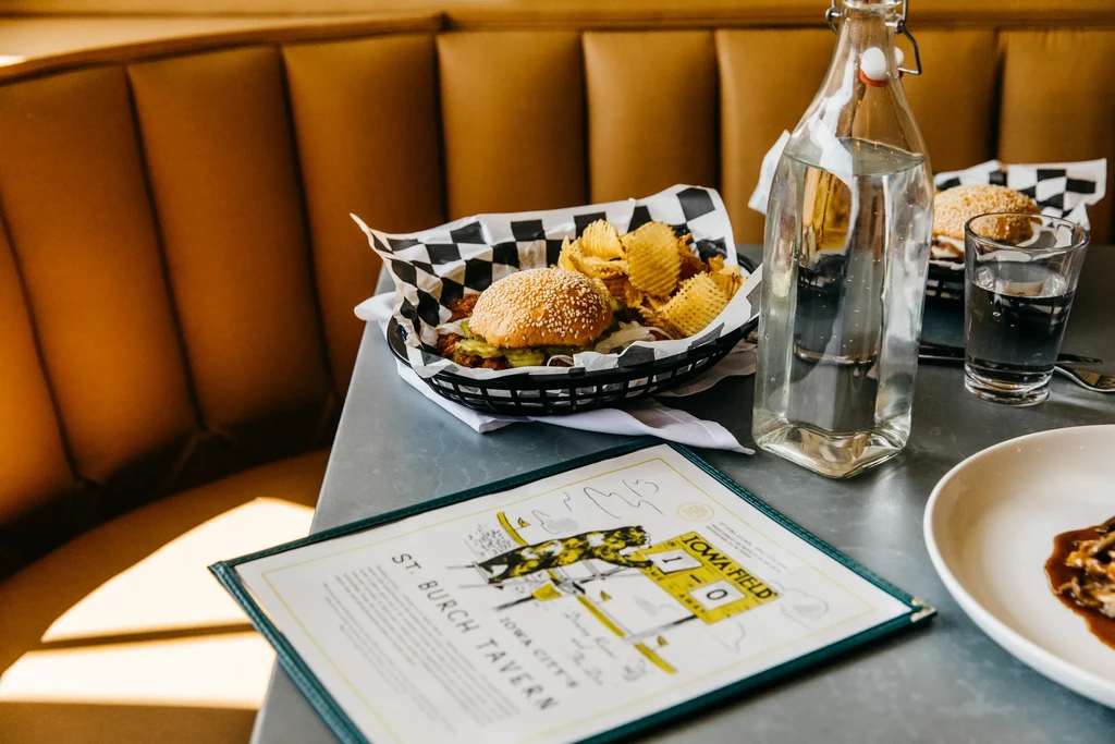 Burger, waffle fries, and water on a tavern table with a menu.