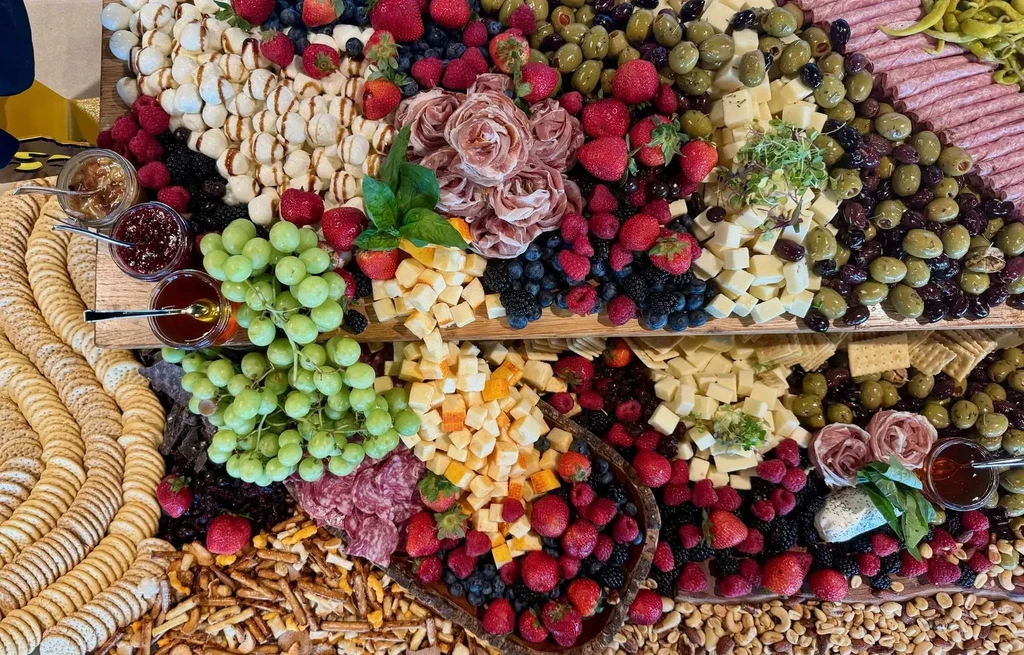 Overflowing charcuterie board with fruits, cheeses, cured meats, crackers, and dips.
