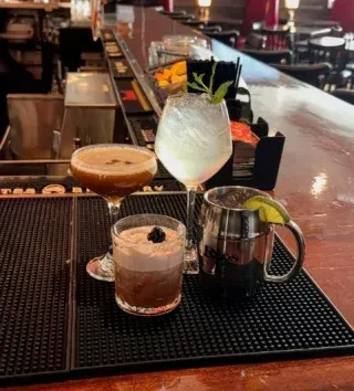 Four distinct cocktails with unique garnishes on a bar mat.