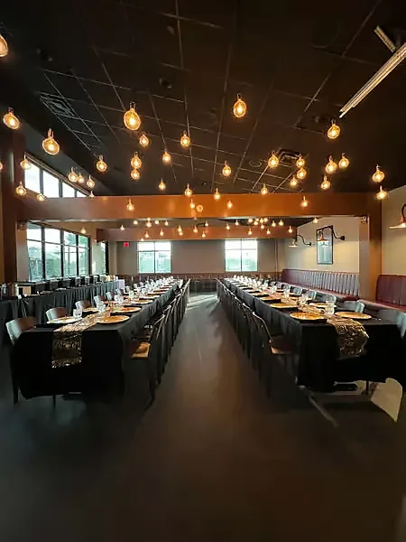 Banquet room set with long tables under hanging edison bulb lights