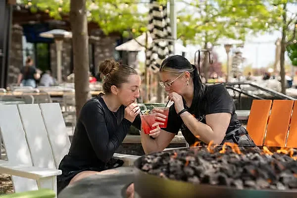 Two guests sipping red cocktails at outdoor patio fire pit