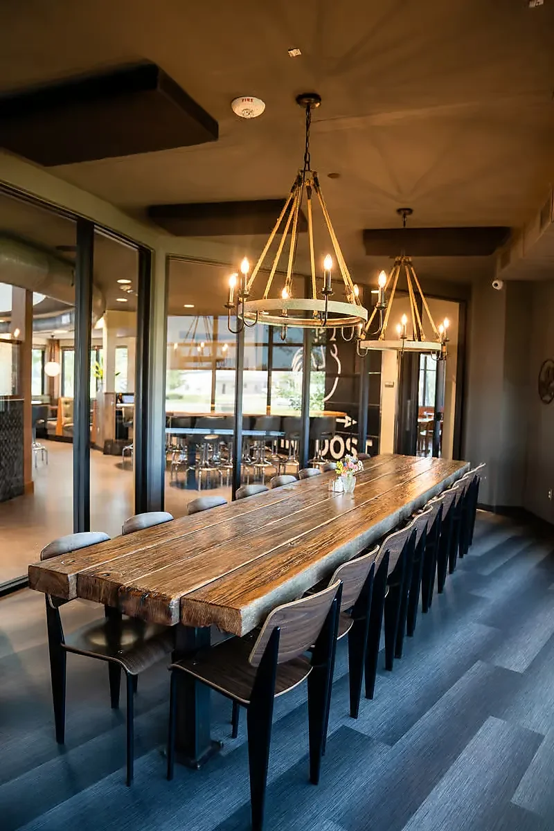 Long wooden communal table under rope chandeliers in private dining room