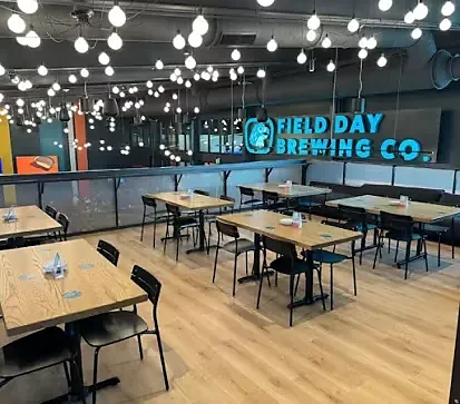 Upper dining area with wood tables and Field Day Brewing sign