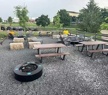 Outdoor gravel patio with picnic tables, fire pit and hay bales