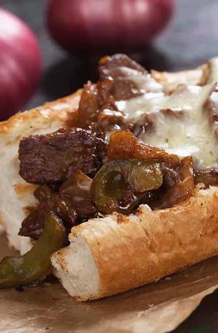Cheesesteak with steak, melted cheese, green peppers, and caramelized onions.