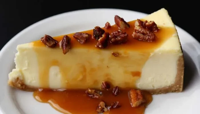 A slice of caramel pecan cheesecake on a white plate.