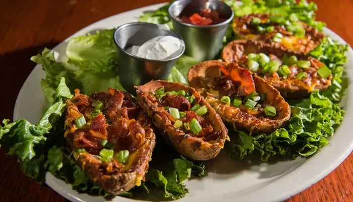 Six potato skins with cheese, bacon, green onions, sour cream, and salsa.