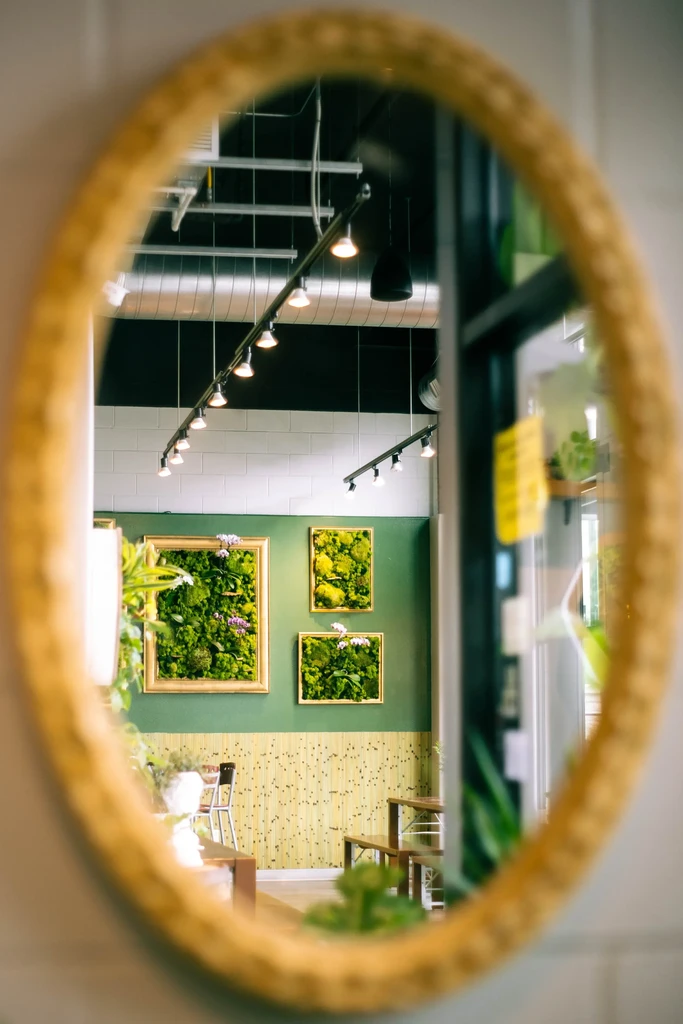 Reflection of modern cafe interior with moss art and green walls.