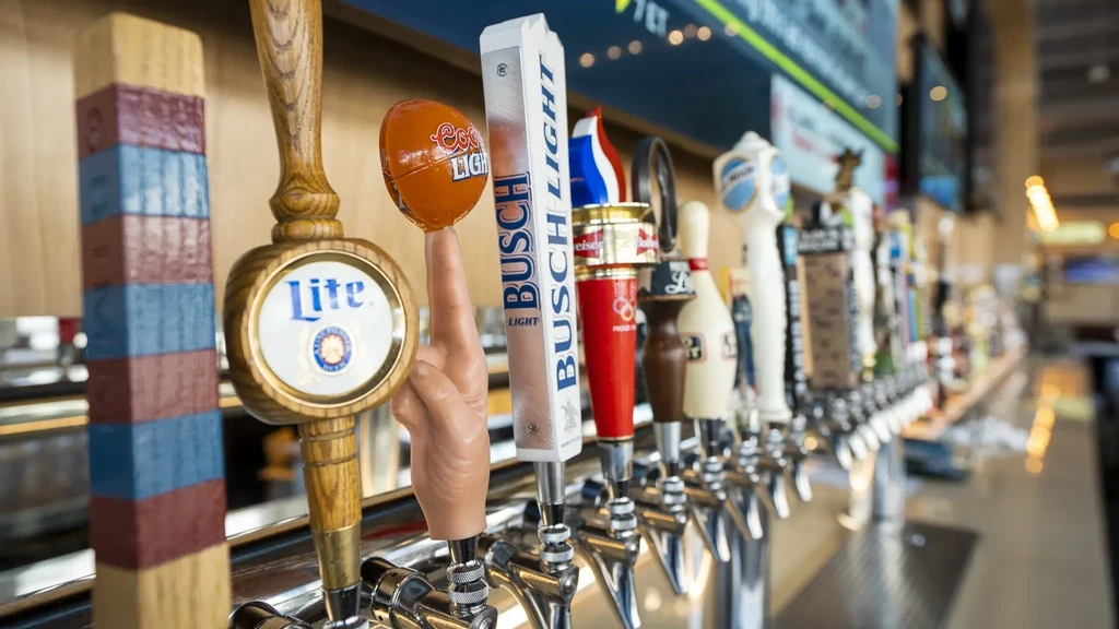 Close-up of a diverse row of branded beer tap handles.