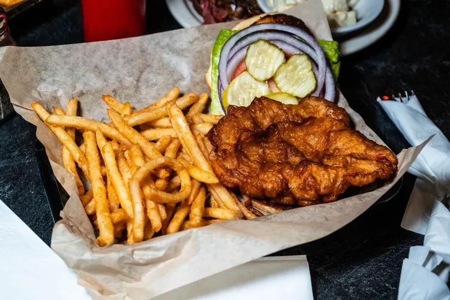 Close-up of fried food, french fries, and a burger in a basket.
