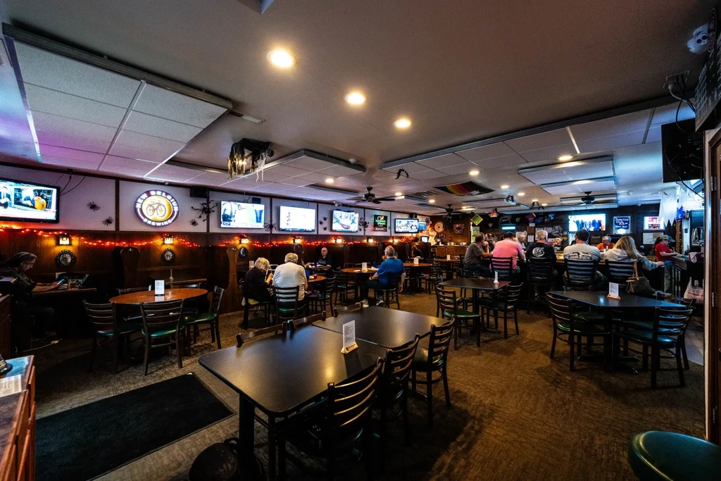Dimly lit sports bar interior with patrons, TVs, and Halloween decorations.