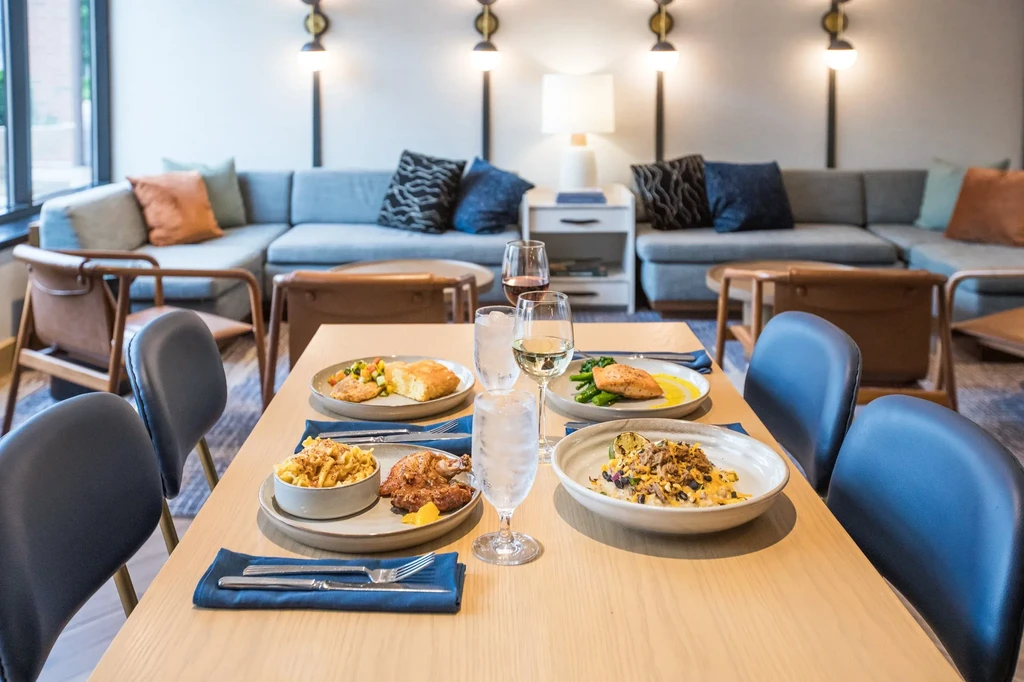 Dining table laden with diverse food and drinks in a modern lounge.
