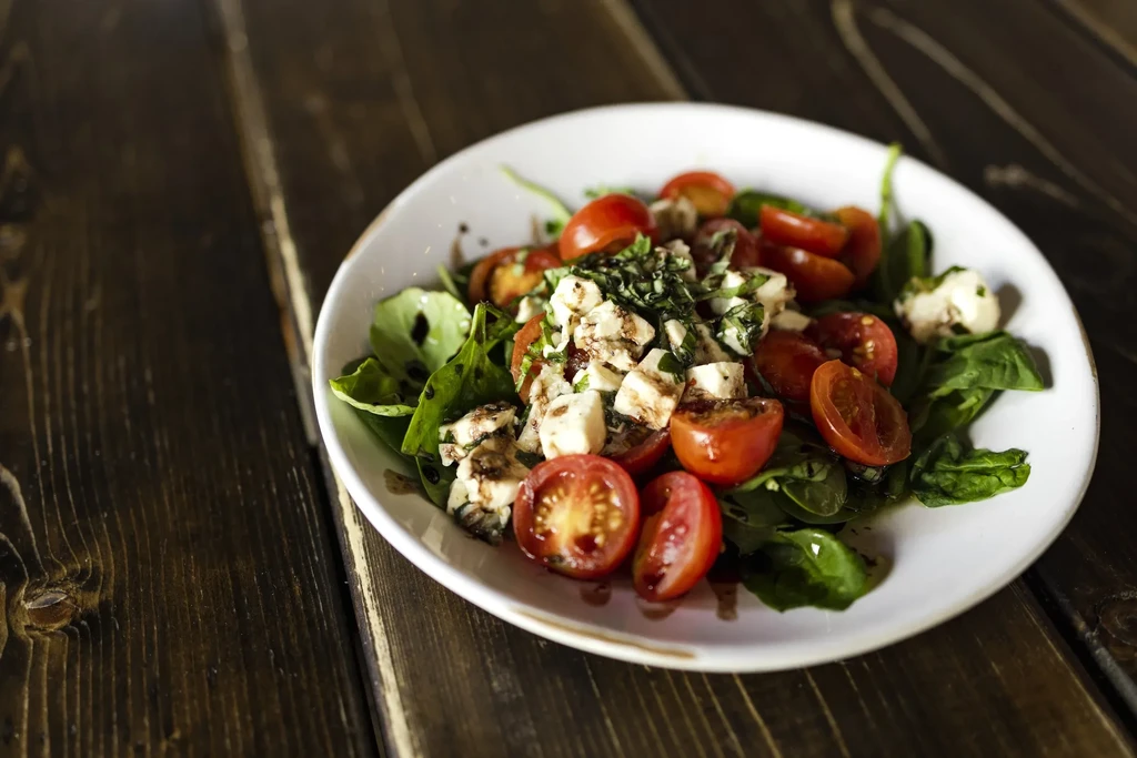 Vibrant cherry tomato, mozzarella, and greens salad with balsamic glaze.
