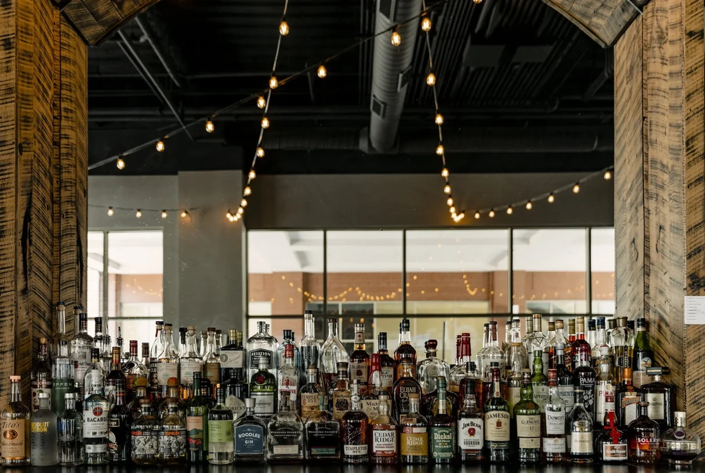 Well-stocked modern bar counter with rows of diverse liquor bottles.