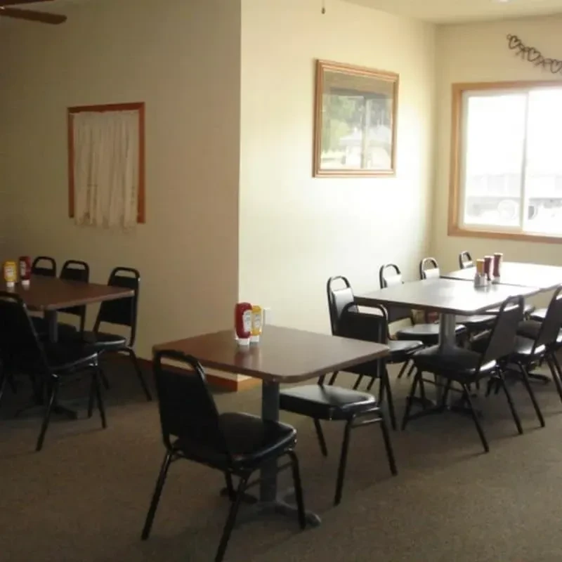 Empty casual diner interior with tables, chairs, and condiment bottles.