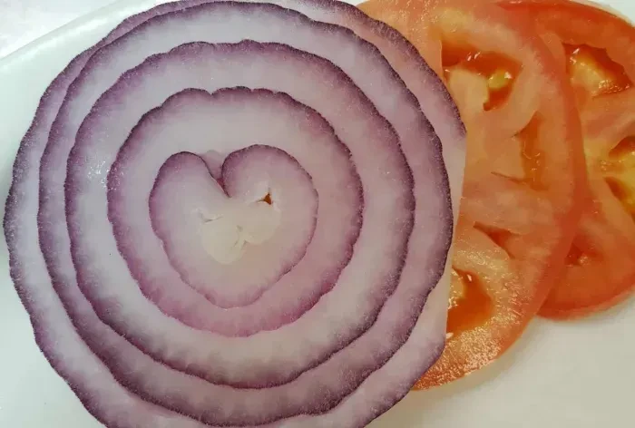 Sliced red onion with heart center and two bright red tomato slices.