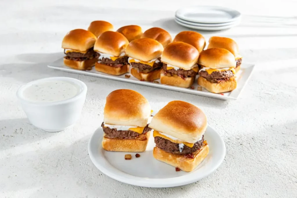 Slider burgers with melted cheese, white sauce, and creamy dipping sauce.