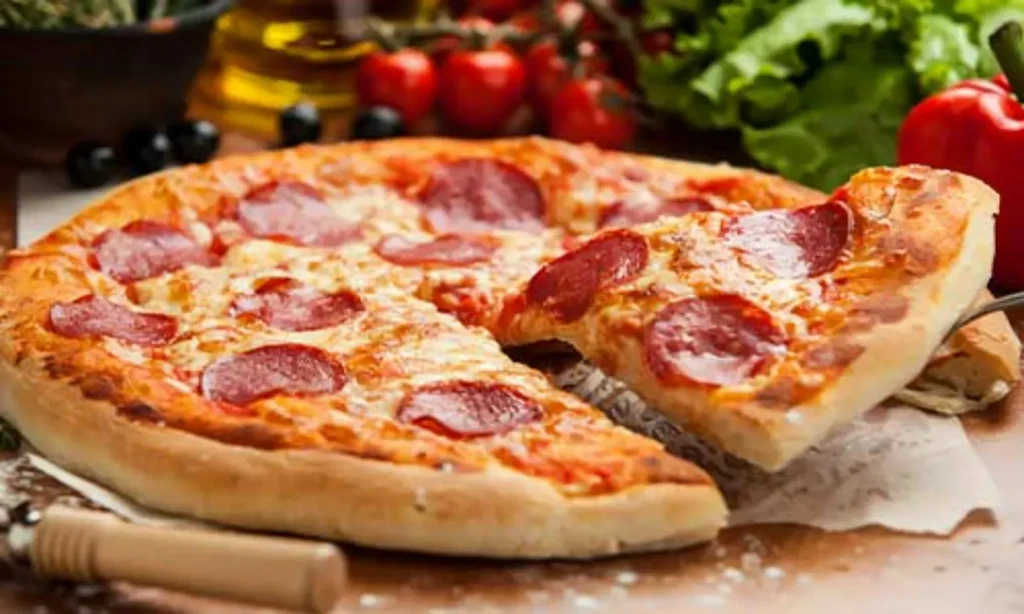 Freshly baked pepperoni pizza with a lifted slice and Italian ingredients.