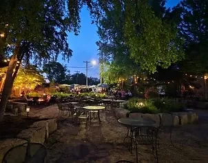Dusk view of an outdoor restaurant patio with illuminated trees.