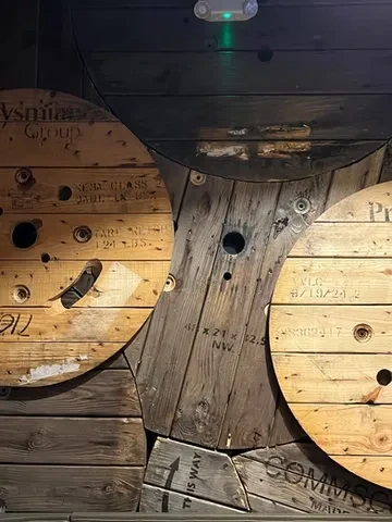 Rustic wooden spools with text cover a dimly lit industrial wall.