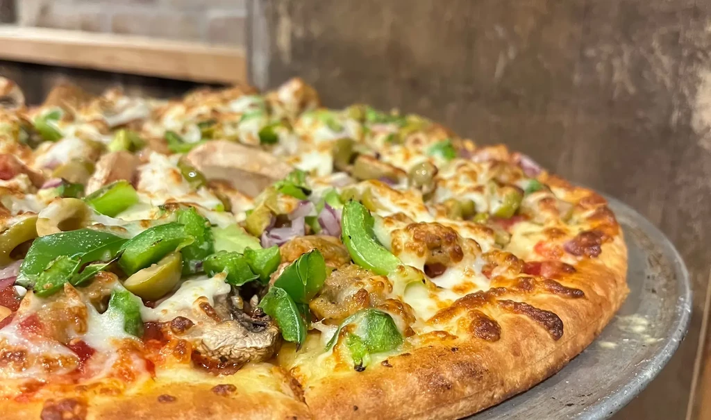 Freshly baked pizza with cheese, bell peppers, olives, and meat.
