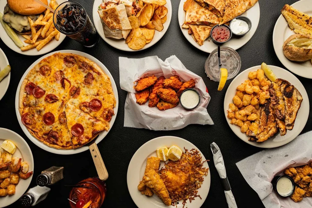 Bright flat-lay of numerous casual restaurant dishes and drinks.