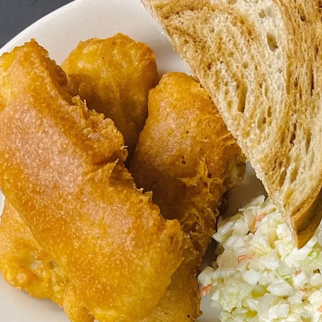 Fried fish, coleslaw, and toast on a white plate.