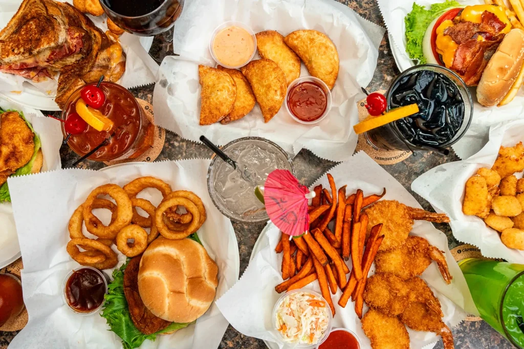 Overhead table flat lay with diverse American food and beverages.