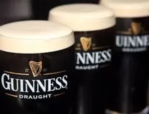 Three Guinness Draught pints with dark beer and creamy foam.