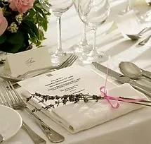Elegant formal dining place setting with menu, lavender, and pink flowers.