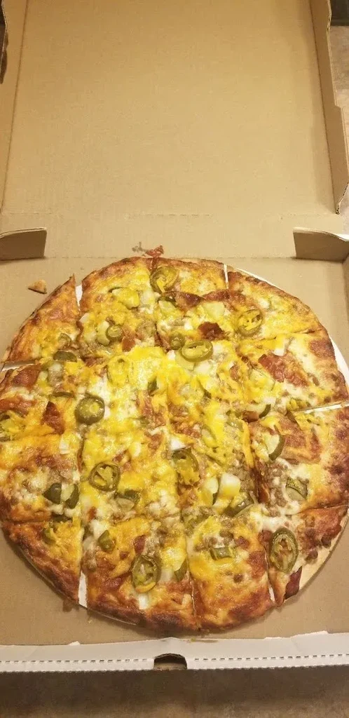 Square-cut pizza with cheese, jalapeños, and meat in an open box.