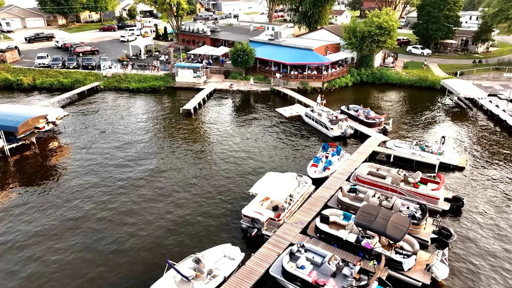 Aerial view: Busy waterside restaurant with outdoor dining and adjacent marina.