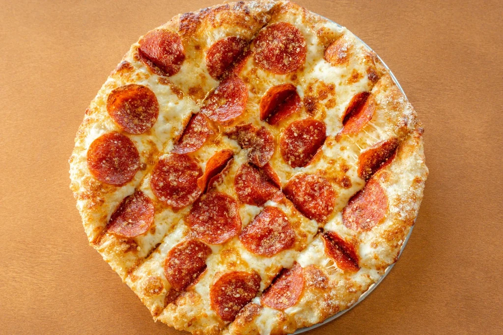Circular pepperoni pizza with melted cheese, crisp pepperoni, and seasonings.