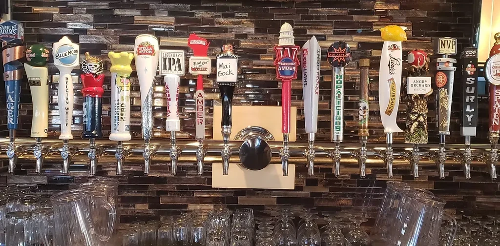 A long row of distinct beer tap handles with clean glassware.