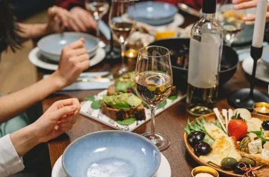 Overhead view of hands, wine, avocado toast, and a charcuterie board.