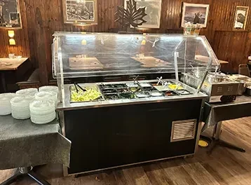 Rustic restaurant with a self-service salad bar, ingredients, and empty plates.