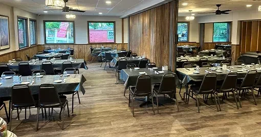 Empty restaurant dining room with many set tables and wood decor.