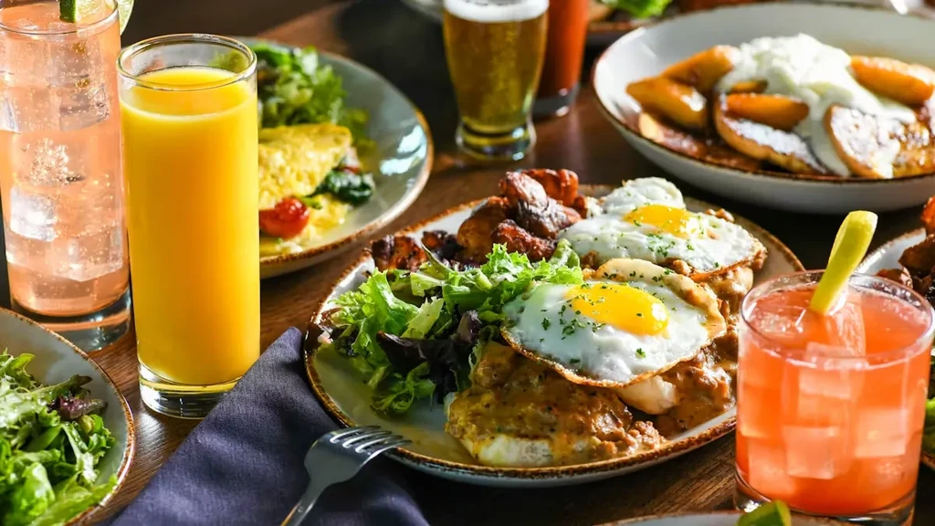 Breakfast table with biscuits, gravy, eggs, salad, and multiple drinks.